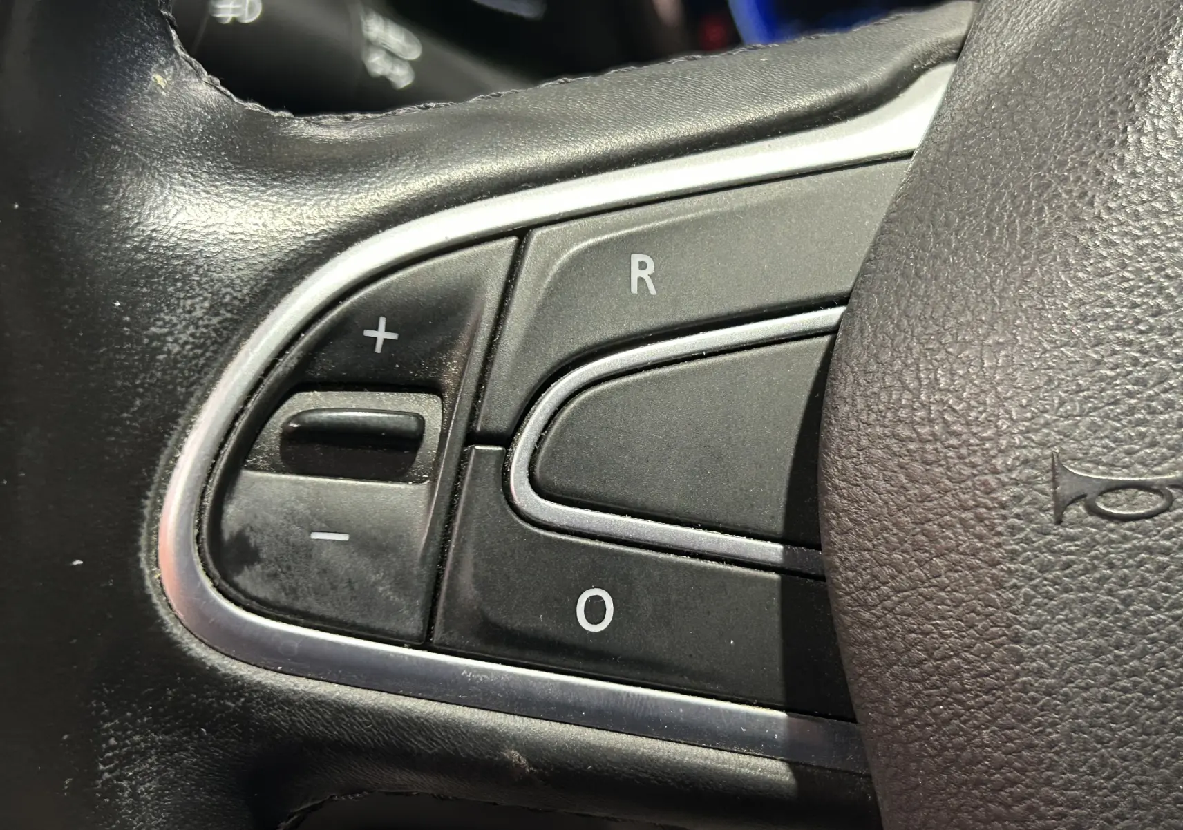 Gros plan sur les commandes du volant noir du Renault Kadjar TCe 130 EDC energy Intens 2017, boutons +, -, R et O visibles.