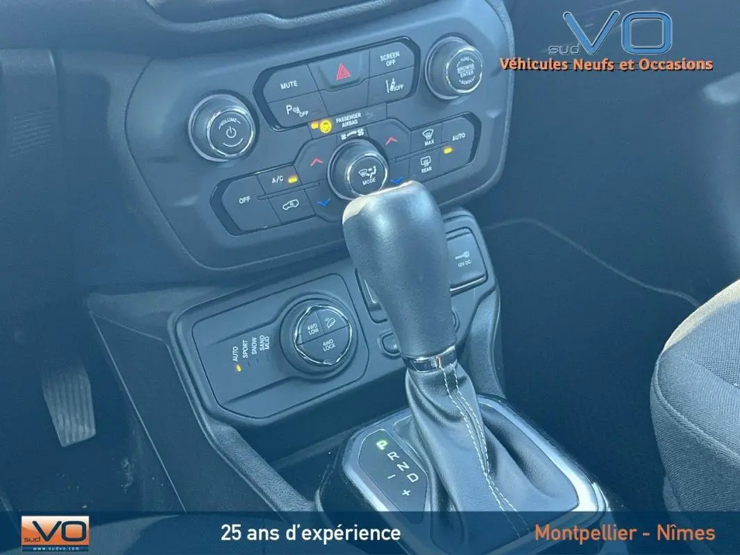 Gros plan sur la console centrale et levier de vitesse automatique du Jeep Renegade gris foncé, avec commandes climatisation et modes de conduite visibles.