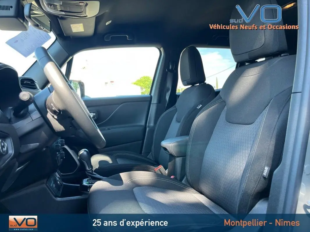 Vue intérieure côté conducteur du Jeep Renegade gris foncé, mettant en valeur les sièges et le volant réglable.