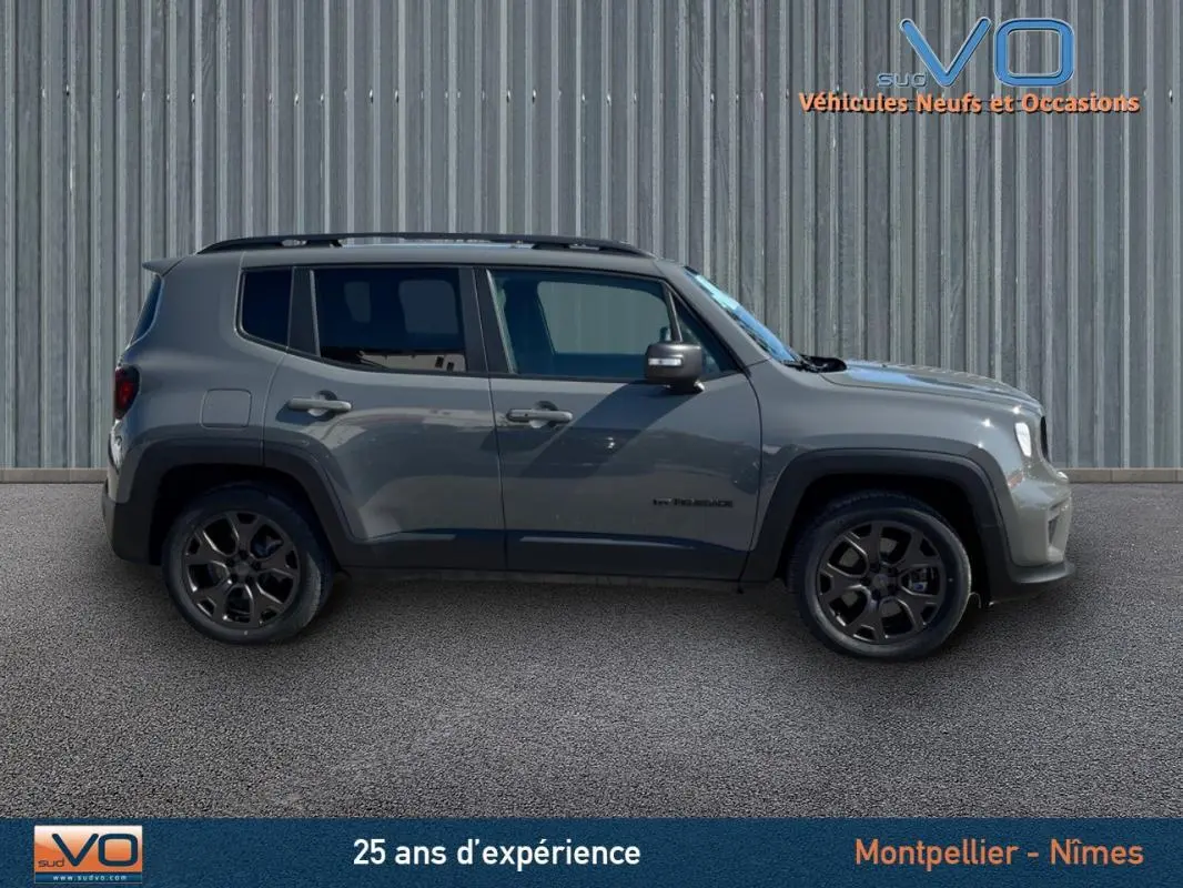 Jeep Renegade gris foncé vu de profil côté gauche, avec barres de toit et jantes alliage 18 pouces.