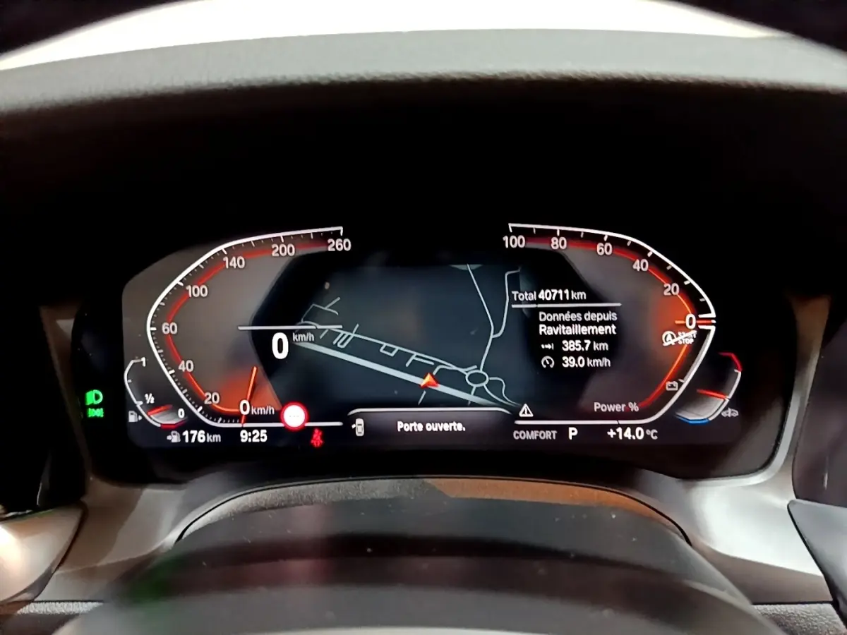 Tableau de bord numérique de BMW Série 3 318i noir, affichage vitesse, navigation et alertes, vue frontale rapprochée.