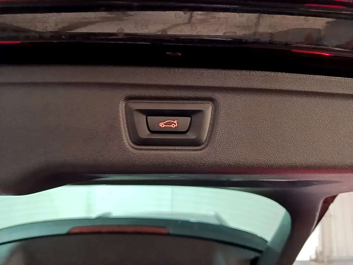 Bouton de fermeture électrique du coffre sur la partie intérieure du hayon d'une BMW Série 3 noire.