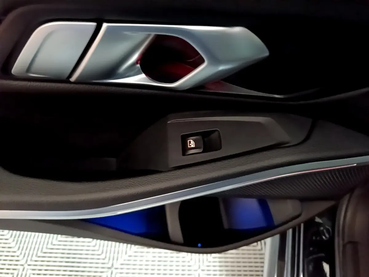 Détail de la poignée intérieure et commande de verrouillage sur la porte côté gauche d'une BMW Série 3 noire.