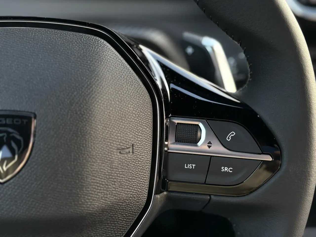 Gros plan sur les commandes multimédia à droite du volant cuir du Peugeot 2008 Hybrid 145 e-DSC6 Allure.