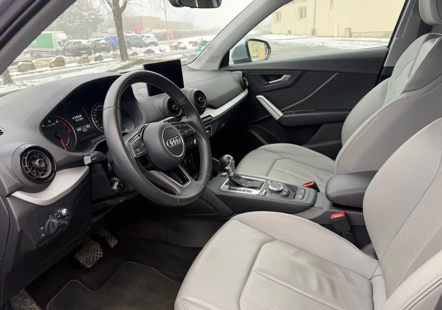 Vue intérieure côté conducteur de l'Audi Q2 2017 avec sellerie similicuir gris clair et tableau de bord moderne.