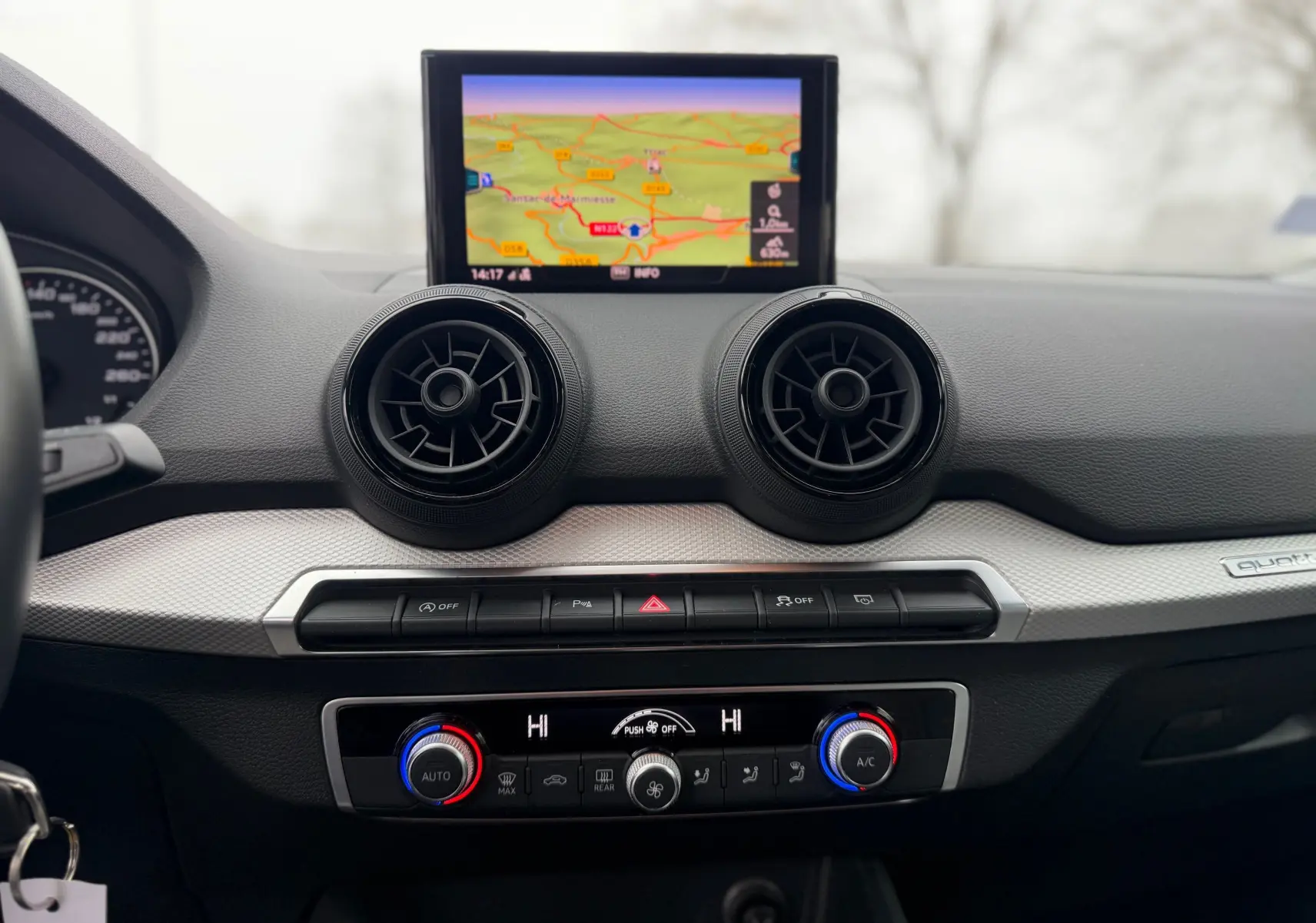 Vue rapprochée du tableau de bord gris d’un Audi Q2 2017 avec écran GPS et commandes de climatisation circulaires.