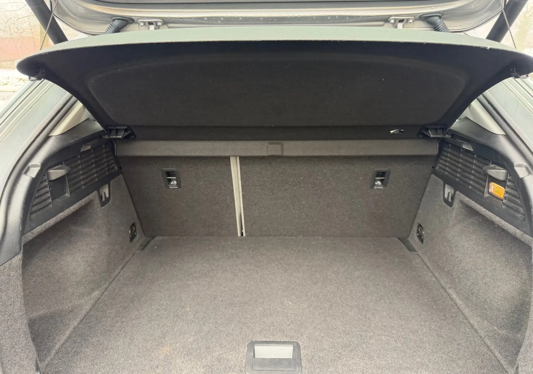 Coffre ouvert vu de l'arrière d'un Audi Q2 gris aluminium, montrant un espace de chargement propre et spacieux.