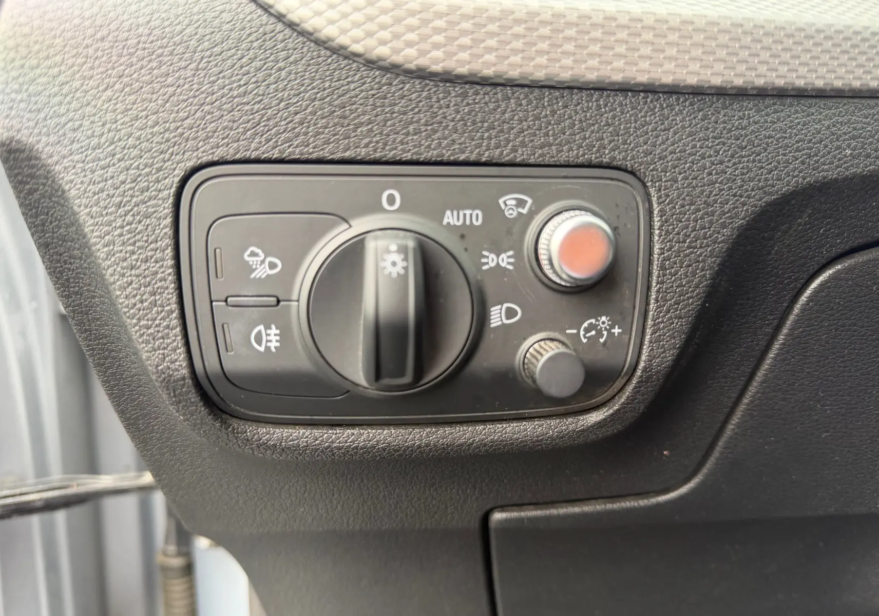 Gros plan sur la commande des phares et réglages lumineux dans l'habitacle de l'Audi Q2 gris aluminium.