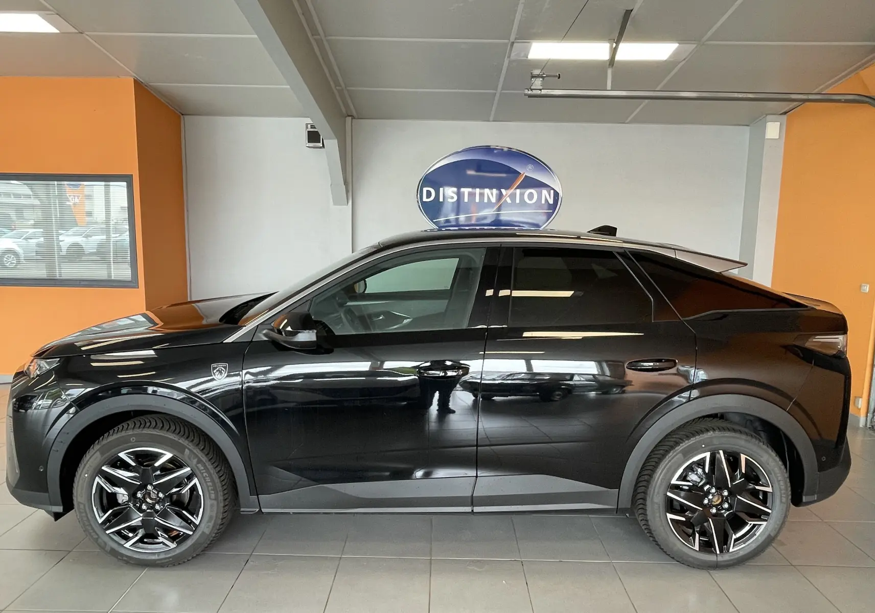Vue de profil côté gauche d’un Peugeot 3008 noir avec jantes alliage noires, stationné en intérieur.
