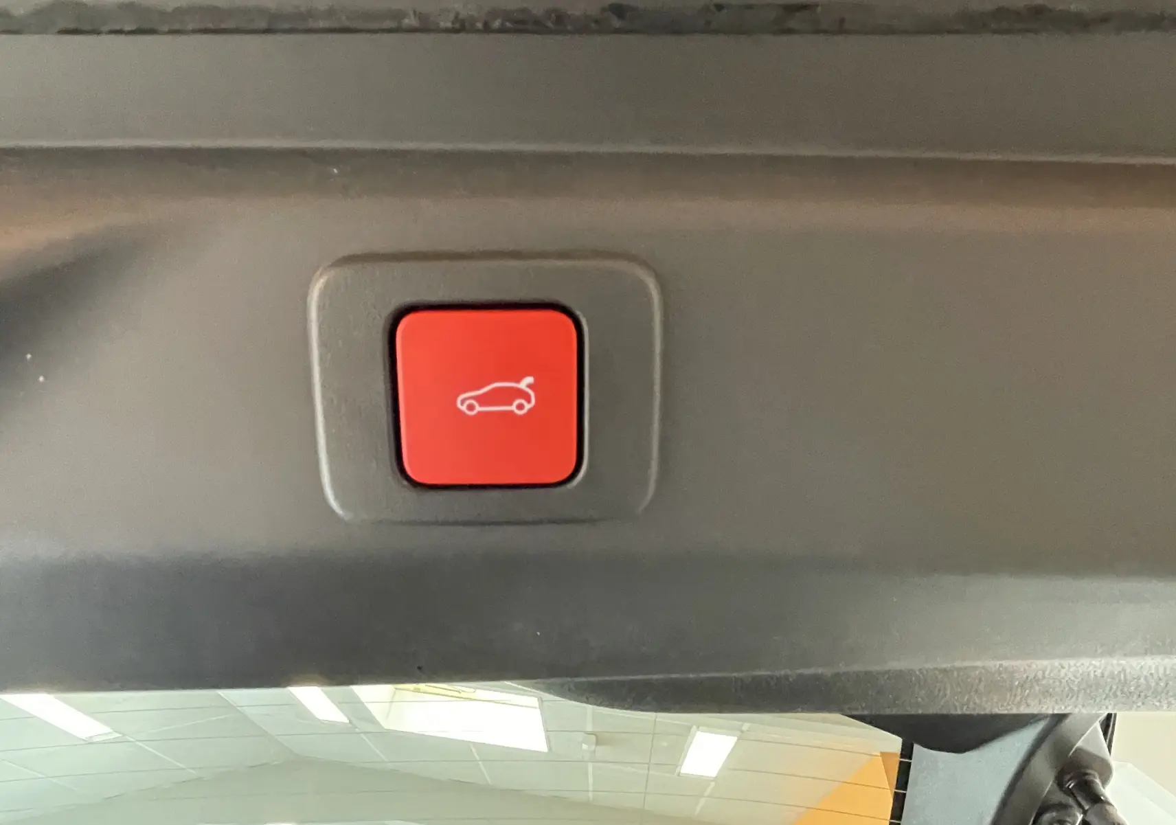 Bouton rouge d'ouverture électrique du coffre visible à l'intérieur d'un Peugeot 3008 noir, vue intérieure arrière.