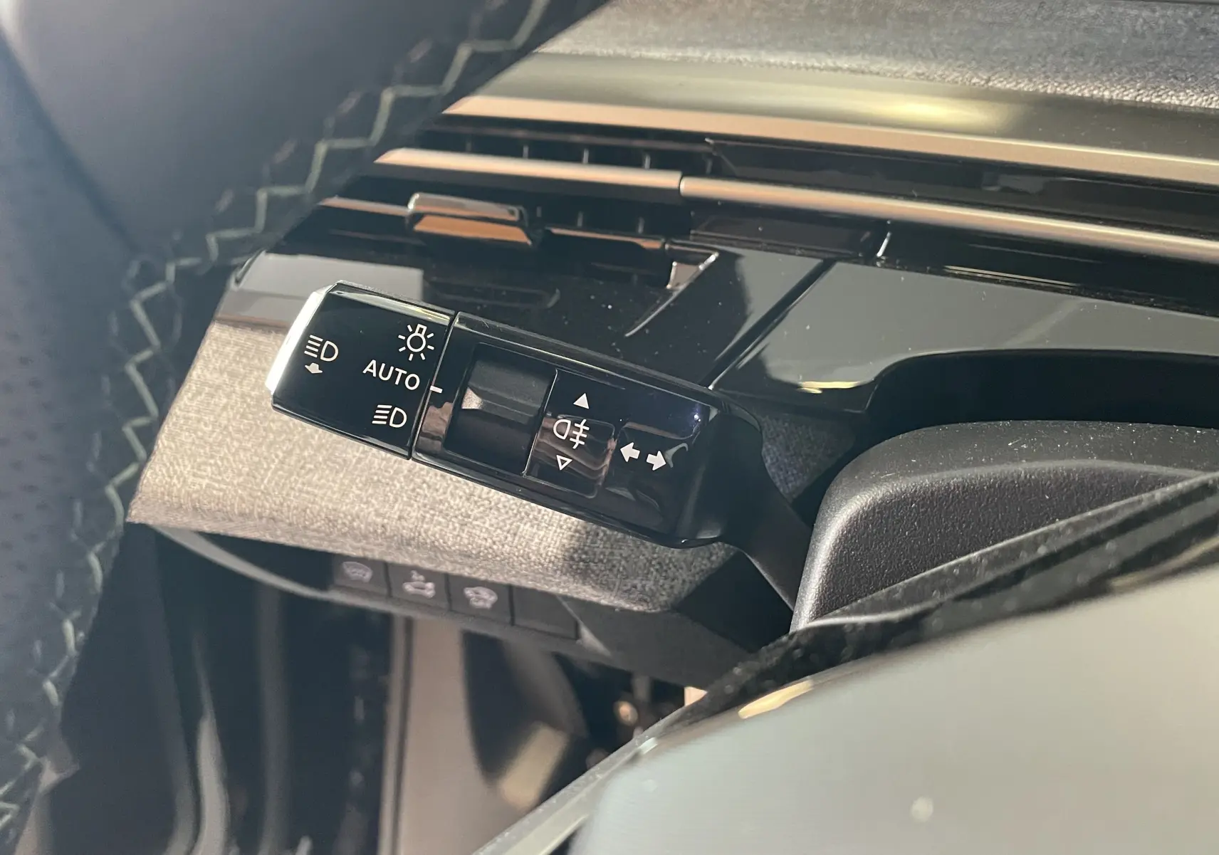 Gros plan sur la commande des feux et clignotants à gauche du volant dans l’habitacle du Peugeot 3008 noir hybride 2026.