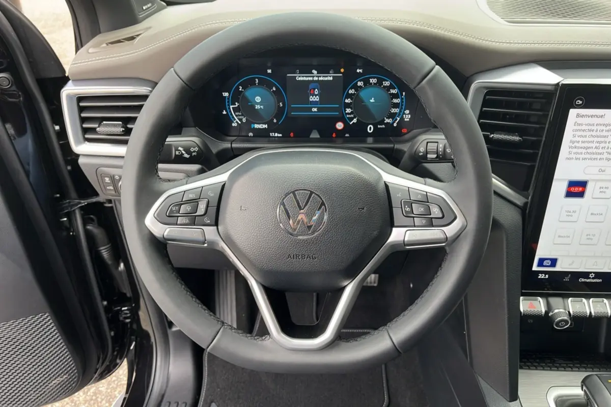 Vue rapprochée du volant cuir multifonctions et du tableau de bord digital du Volkswagen Amarok noir 2025.