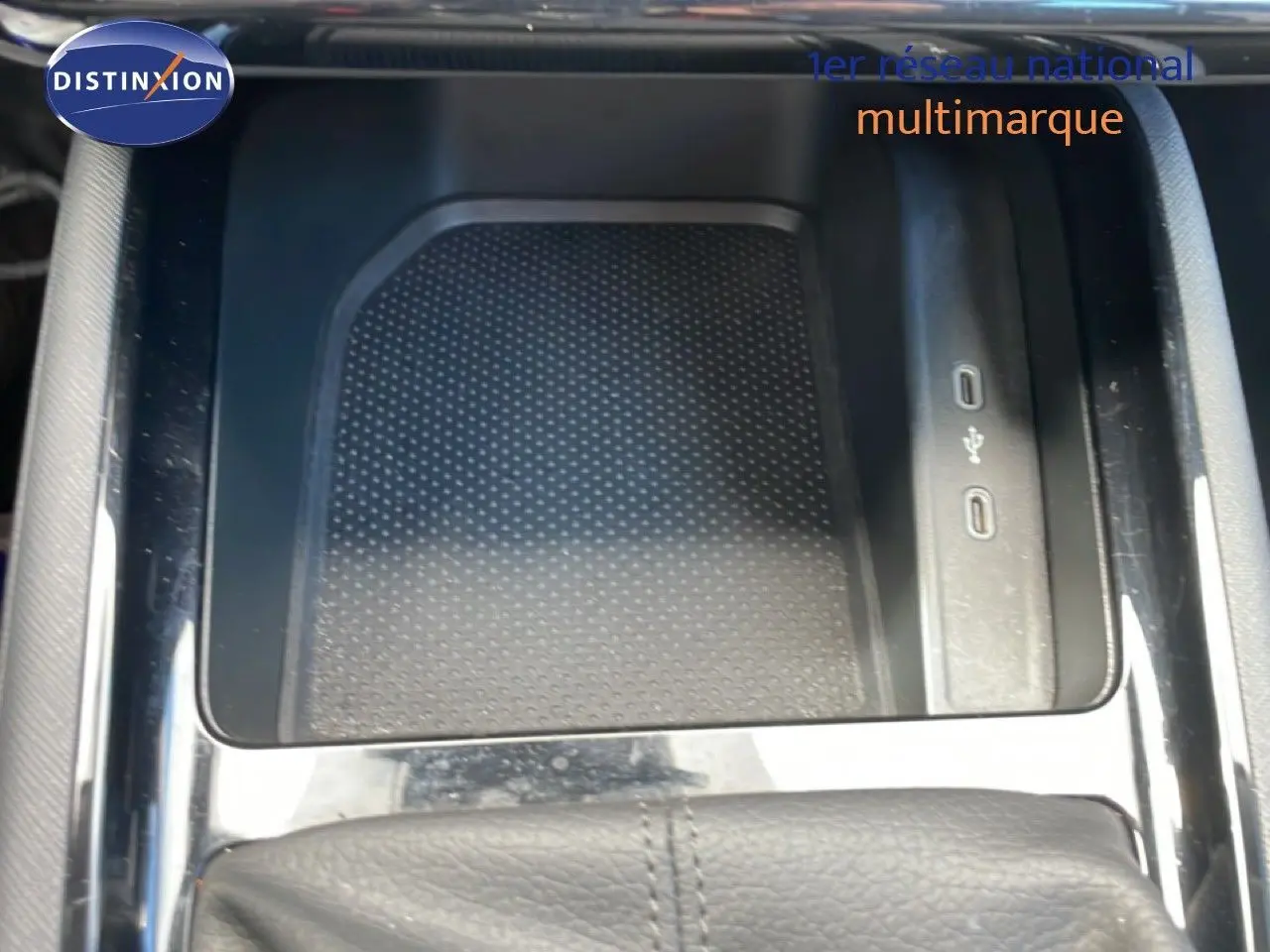 Gros plan sur la console centrale d’une Skoda Scala blanche, mettant en valeur le rangement avec ports USB et la finition noire brillante.