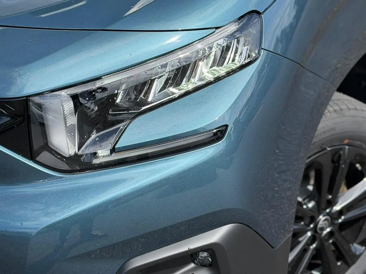 Gros plan sur le phare avant droit bleu Kiama du Citroën Berlingo Multispace 2026 avec jante alliage noire.