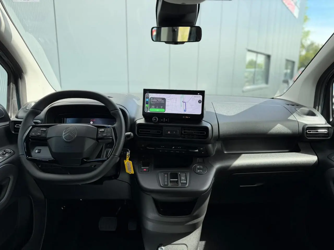 Vue intérieure avant du Citroën Berlingo Multispace 2026, tableau de bord noir avec écran tactile et volant multifonctions.