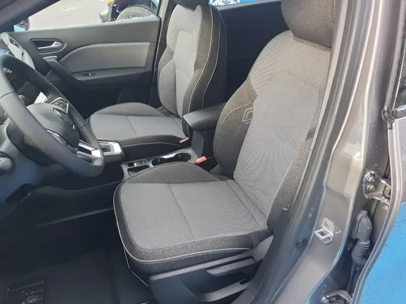 Vue intérieure côté conducteur du Renault Captur gris Cassiopée 2025, sièges tissu gris avec accoudoir central.