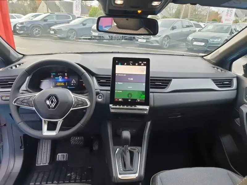 Vue de face de l'intérieur du Renault Captur gris Cassiopée, avec tableau de bord moderne et écran tactile vertical.