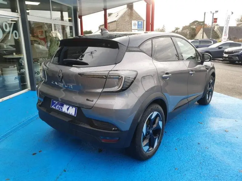 Vue 3/4 arrière droite du Renault Captur 2025 gris Cassiopée avec vitres surteintées et jantes alu bicolores.