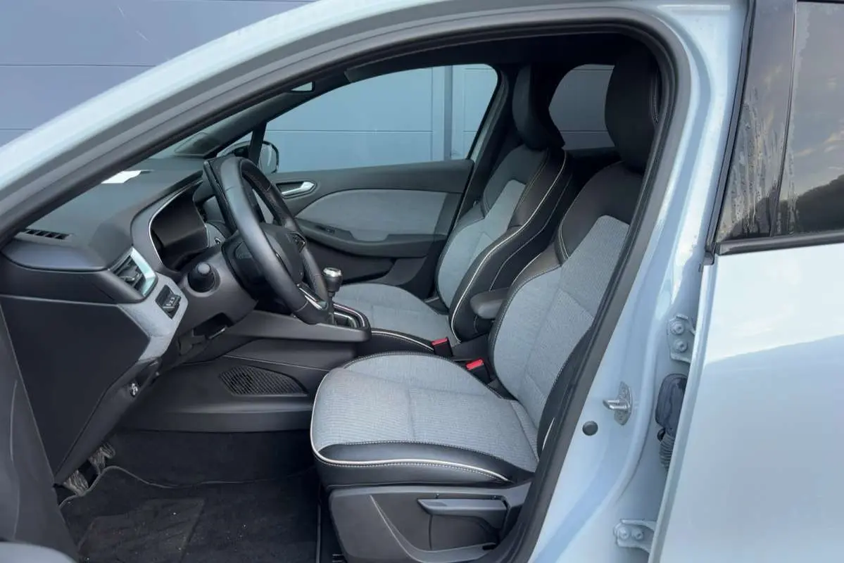 Vue intérieure côté conducteur de la Renault Clio 2025 gris rafale, sièges bi-matière et volant cuir multifonctions.