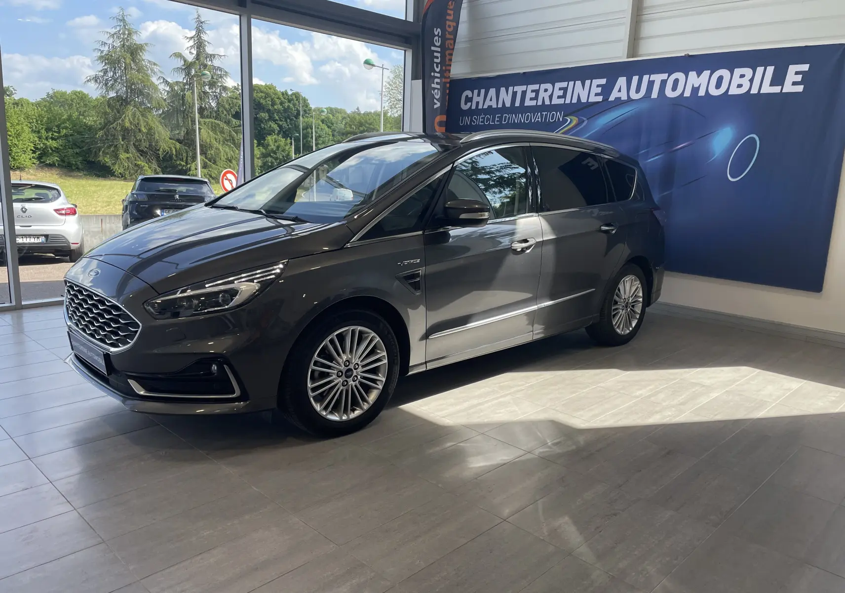 Ford S-MAX Vignale gris magnetic en 3/4 avant droit dans un showroom avec logo Chantreine Automobile visible.