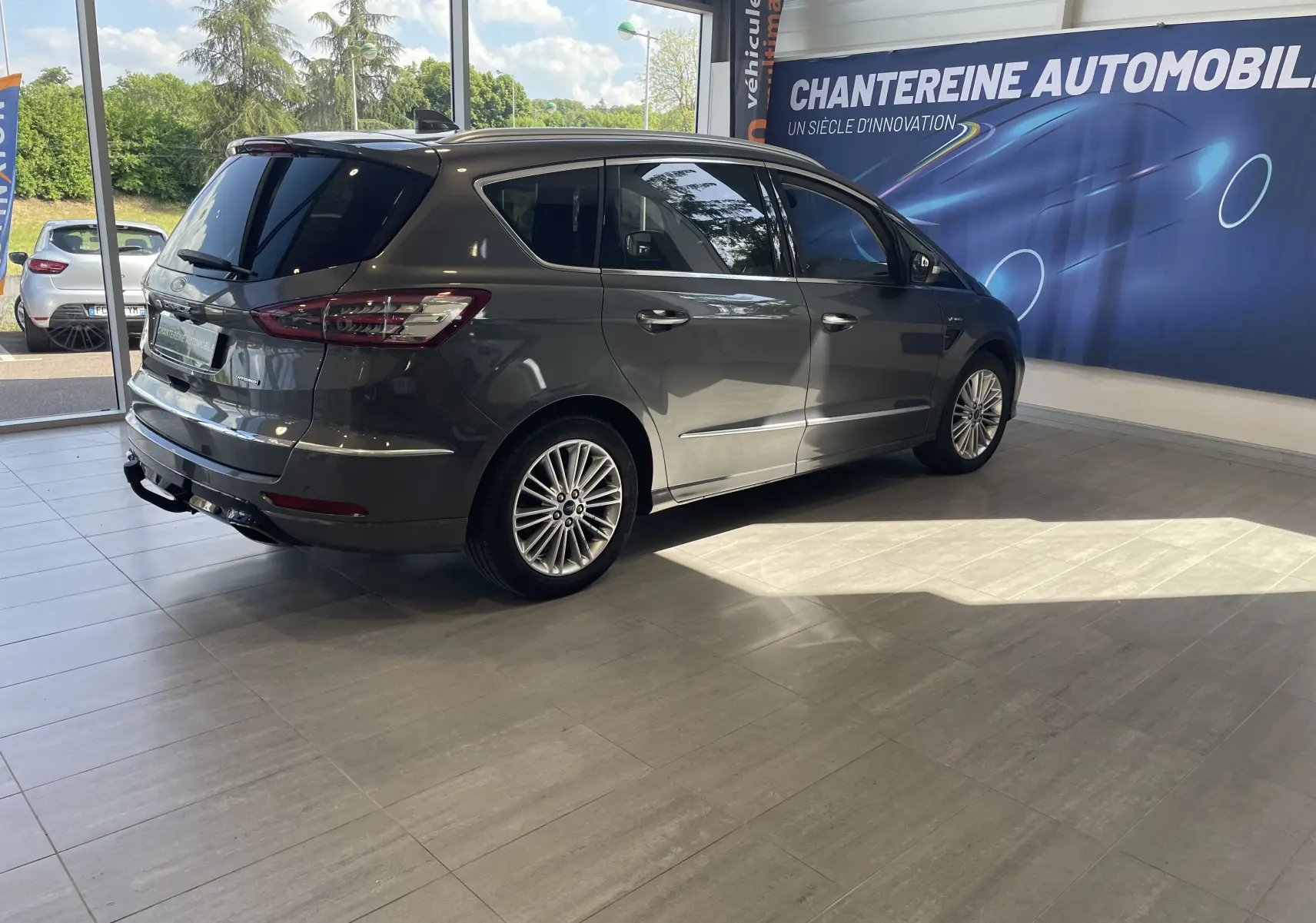Ford S-MAX Vignale gris magnetic vu de trois quarts arrière droit dans un showroom lumineux.