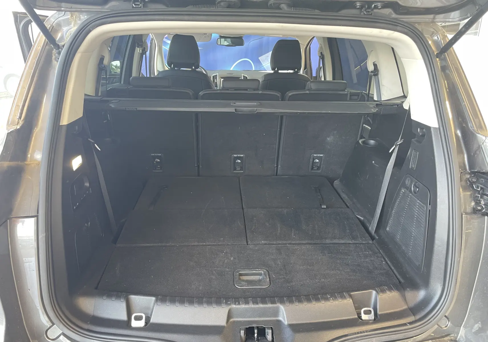 Vue arrière du coffre spacieux du Ford S-MAX Vignale gris magnetic 2022 avec sièges rabattus et cache-bagages déployé.