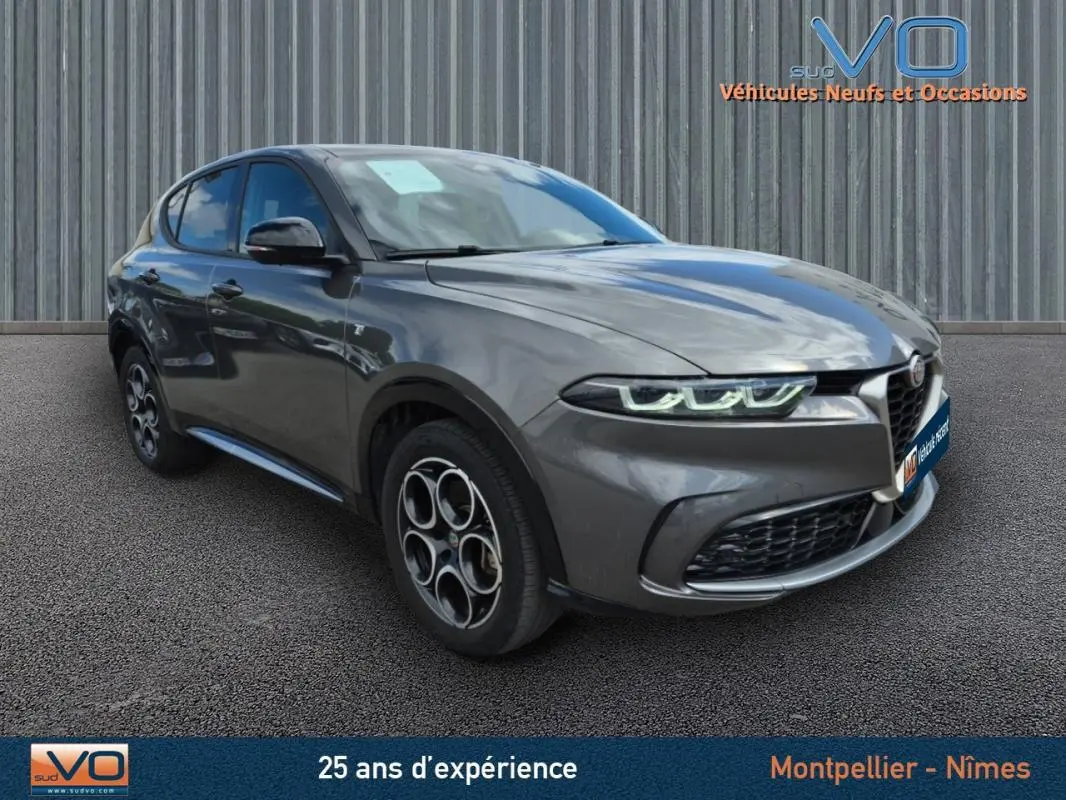 Vue 3/4 avant d'une Alfa Romeo Tonale gris métallisé avec jantes alliage 18 pouces et phares LED allumés.