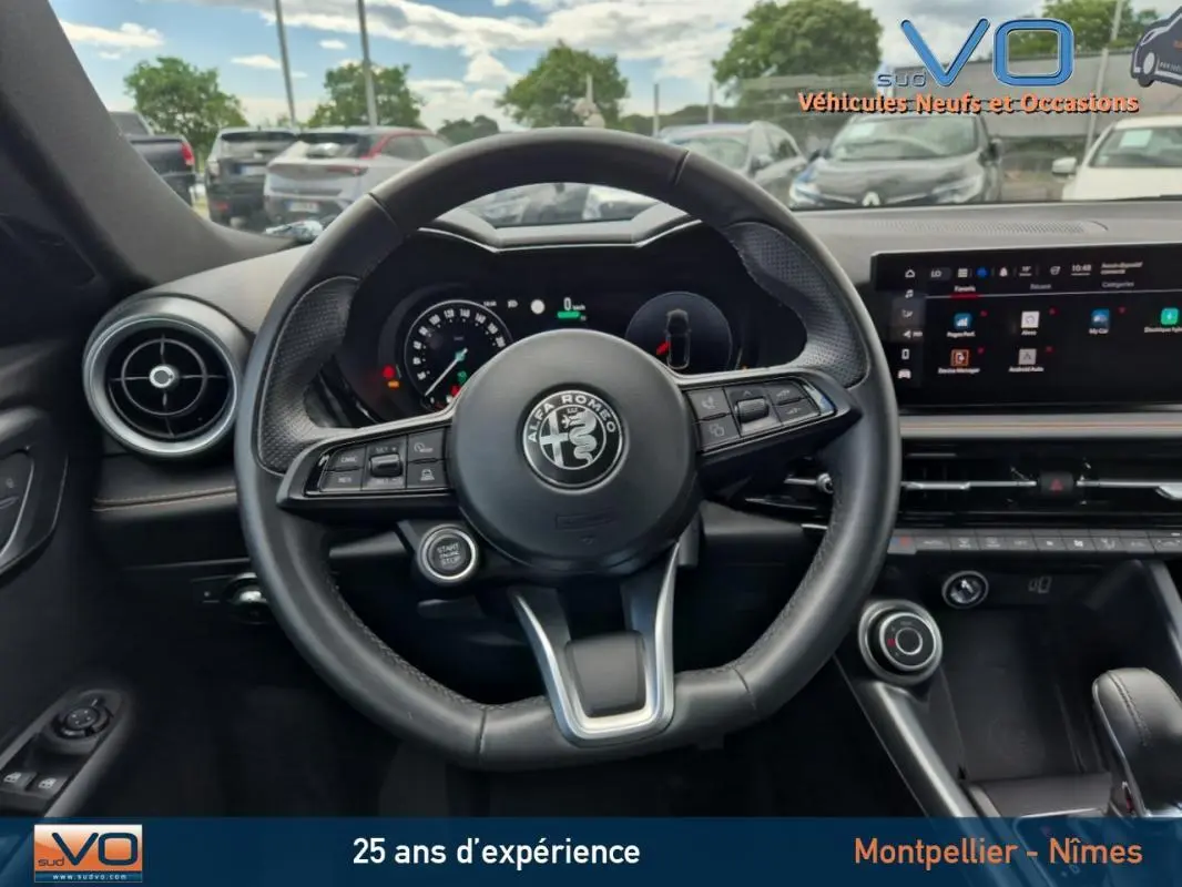 Vue centrée sur le volant sport de l'Alfa Romeo Tonale gris 2023 avec tableau de bord digital et écran tactile.