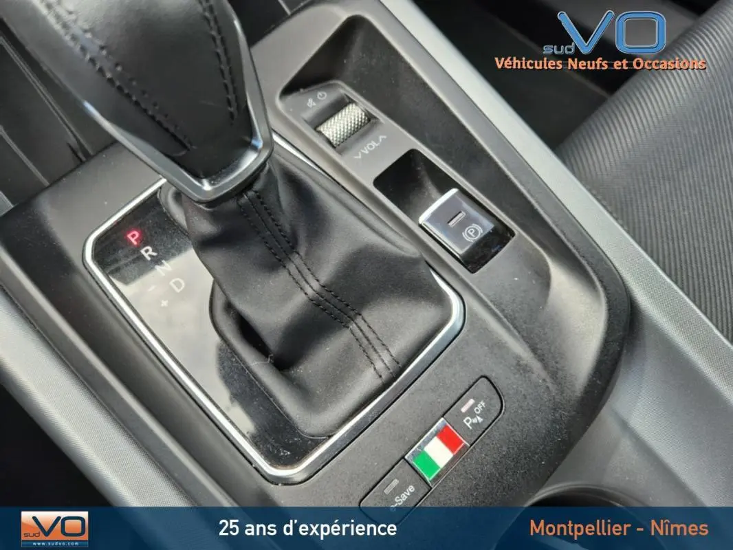 Gros plan sur la console centrale de l'Alfa Romeo Tonale 2023, avec levier de vitesse automatique et badge tricolore italien.