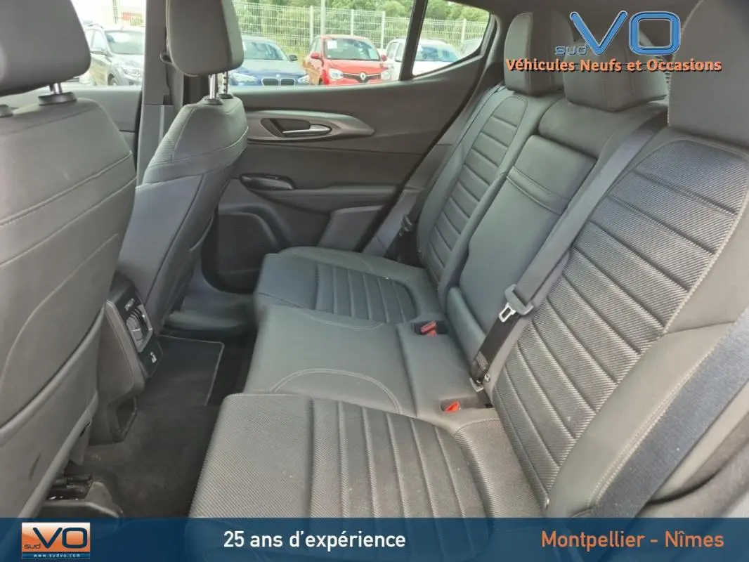 Vue intérieure arrière montrant les sièges arrière en cuir gris de l'Alfa Romeo Tonale 2023, avec accoudoir central et ceintures visibles.