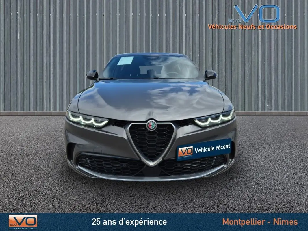Vue frontale d'une Alfa Romeo Tonale gris métallisé 2023 avec feux LED allumés et calandre caractéristique en V.