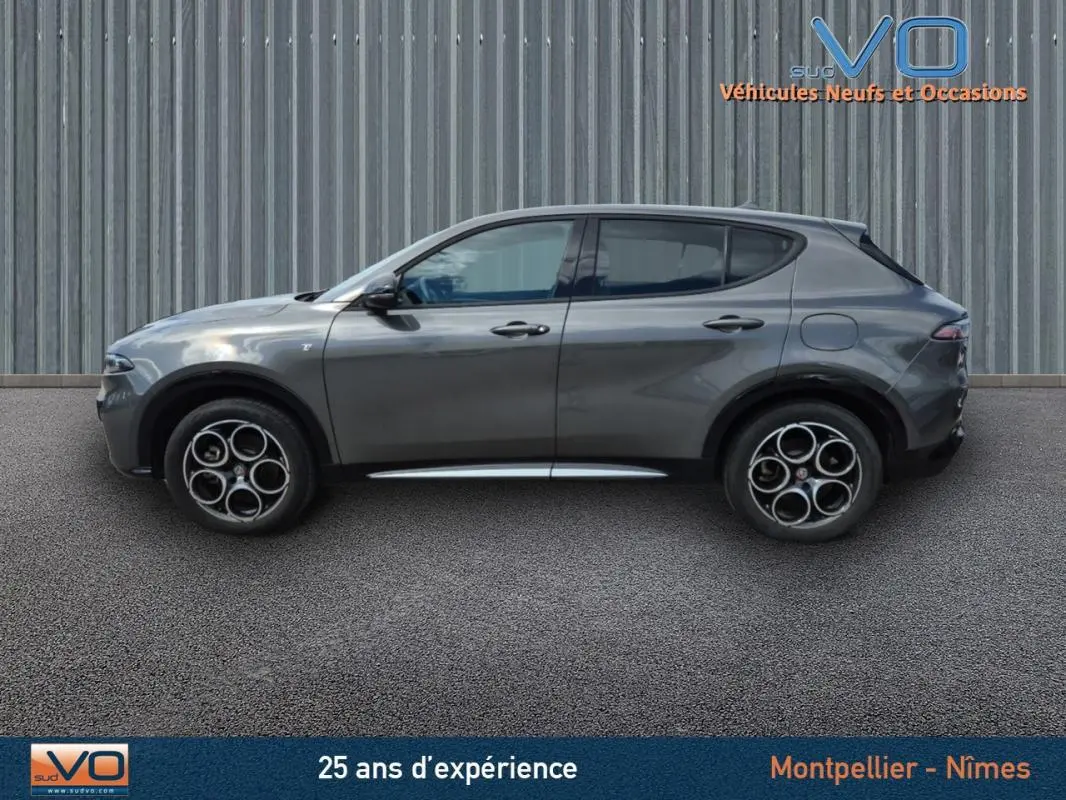 Profil latéral droit d'une Alfa Romeo Tonale gris métallisé 2023 avec jantes alliage 18 pouces sur fond urbain.