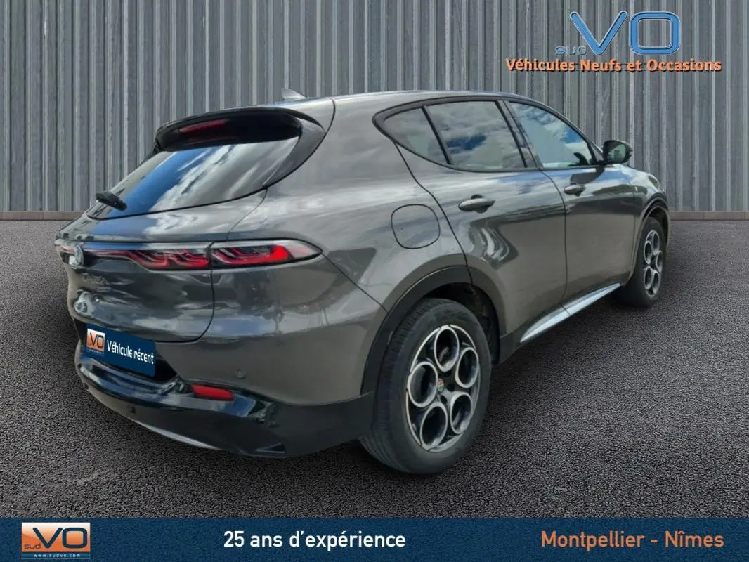 Vue 3/4 arrière droite d'une Alfa Romeo Tonale grise 2023 avec jantes alliage 18 pouces et feux arrière allumés