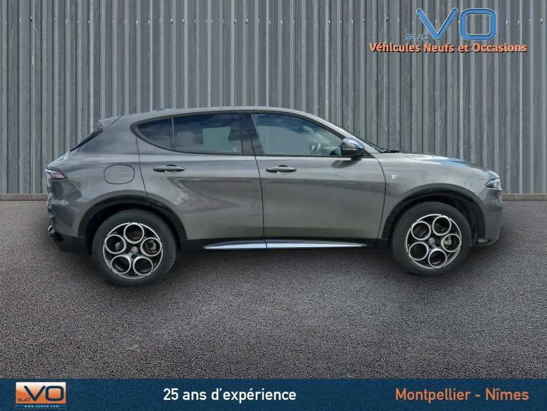 Profil latéral droit de l'Alfa Romeo Tonale gris 2023 avec jantes alliage 18 pouces et lignes épurées du SUV hybride rechargeable.