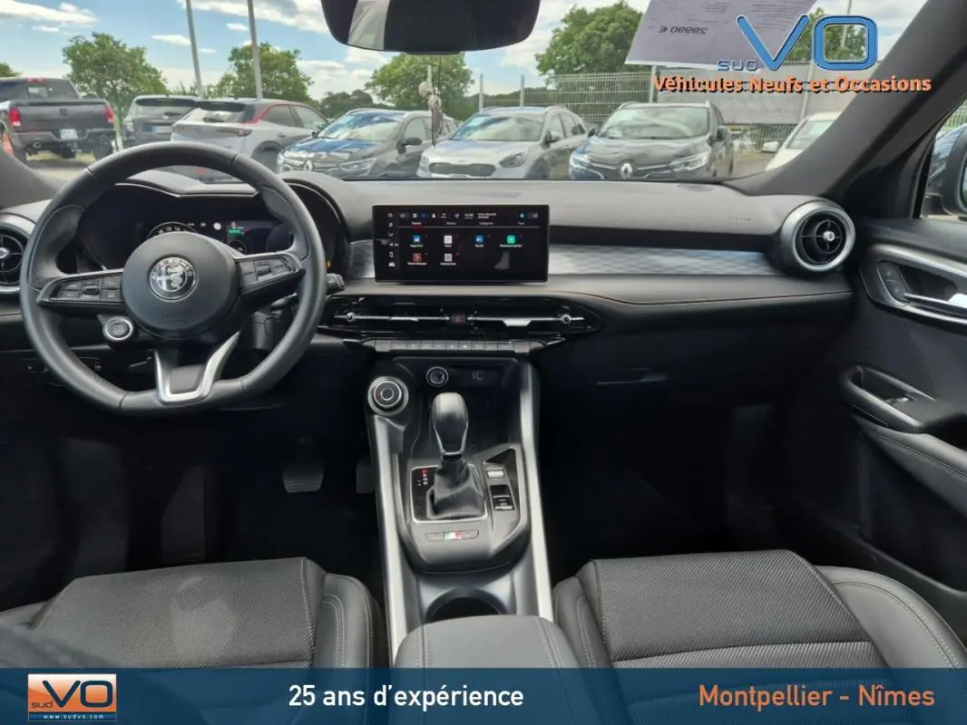 Intérieur de l'Alfa Romeo Tonale 2023 en vue frontale, volant sport noir et écran tactile central moderne.