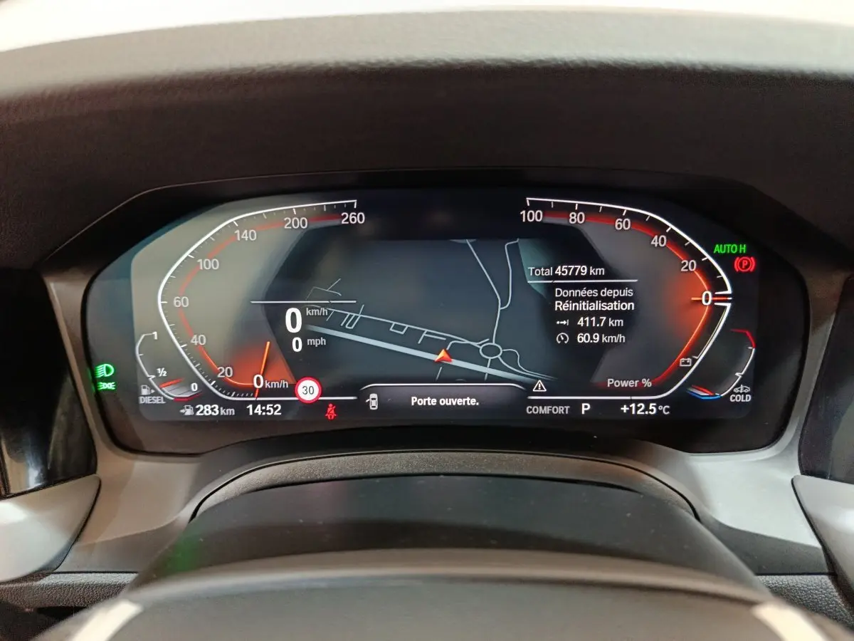 Tableau de bord numérique de BMW Série 3 316d 2022, affichage vitesse, navigation et alertes, vue frontale rapprochée.