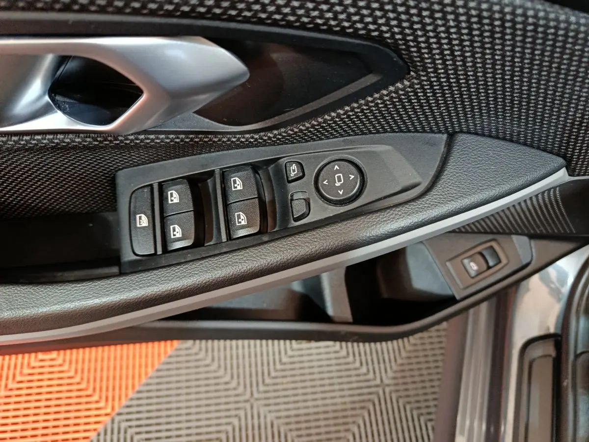 Vue rapprochée du panneau de commandes côté conducteur de la BMW Série 3 gris clair, avec boutons de vitres et rétroviseurs.