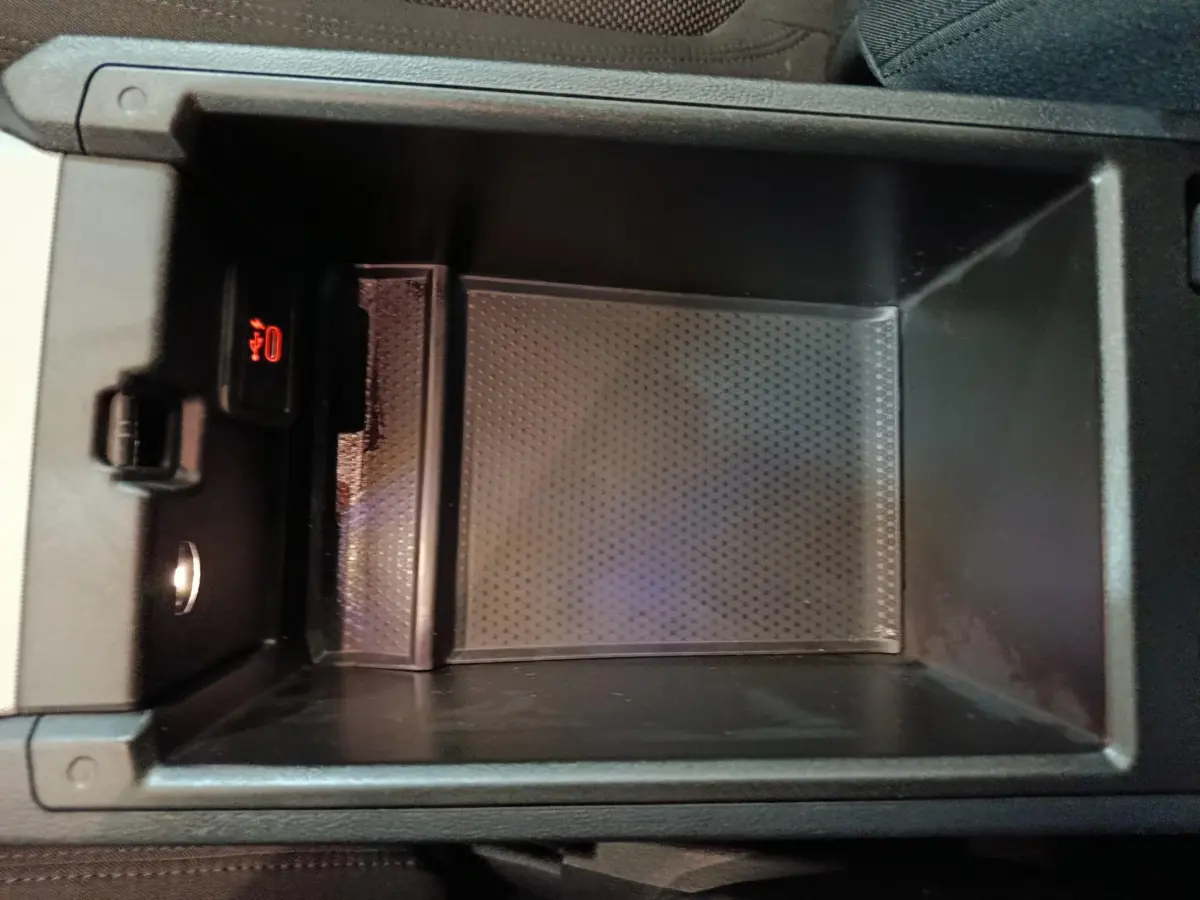 Vue rapprochée de la console centrale ouverte d'une BMW Série 3 gris clair, montrant un espace de rangement avec prise USB.