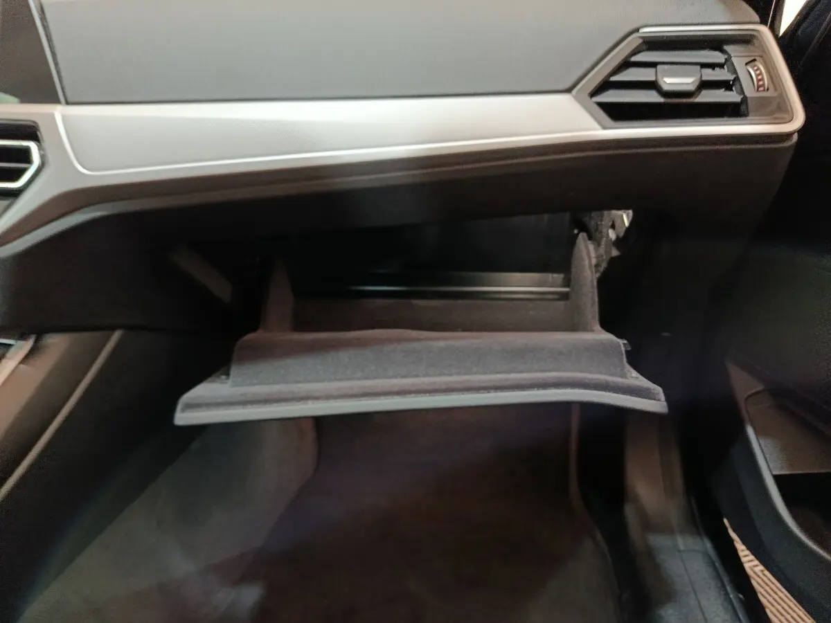 Gros plan sur la boîte à gants ouverte côté passager de la BMW Série 3 316d gris clair, intérieur noir.