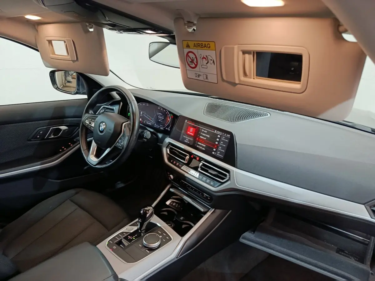 Intérieur BMW Série 3 316d 2022 vu côté conducteur, tableau de bord moderne avec écran tactile et volant cuir.