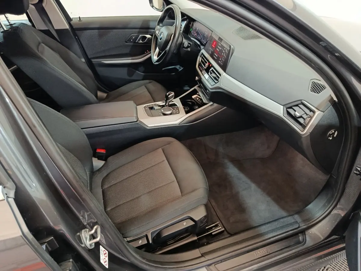 Vue intérieure côté conducteur de la BMW Série 3 316d 2022 avec sièges noirs et tableau de bord moderne.