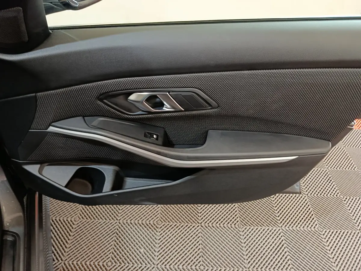Gros plan sur la porte côté gauche de la BMW Série 3 316d 2022, avec garniture noire et insert argenté.