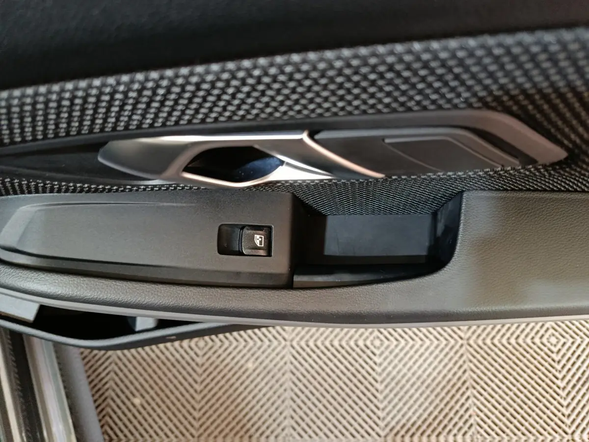 Poignée intérieure de porte côté gauche avec bouton de commande de vitre sur BMW Série 3 gris clair 316d Business Design 2022.