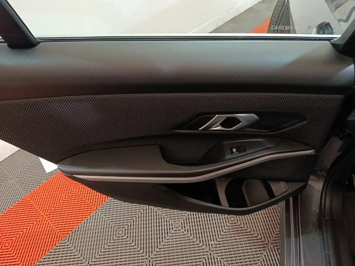 Vue côté gauche de la porte intérieure noire de la BMW Série 3 316d Business Design 2022 avec poignée argentée.