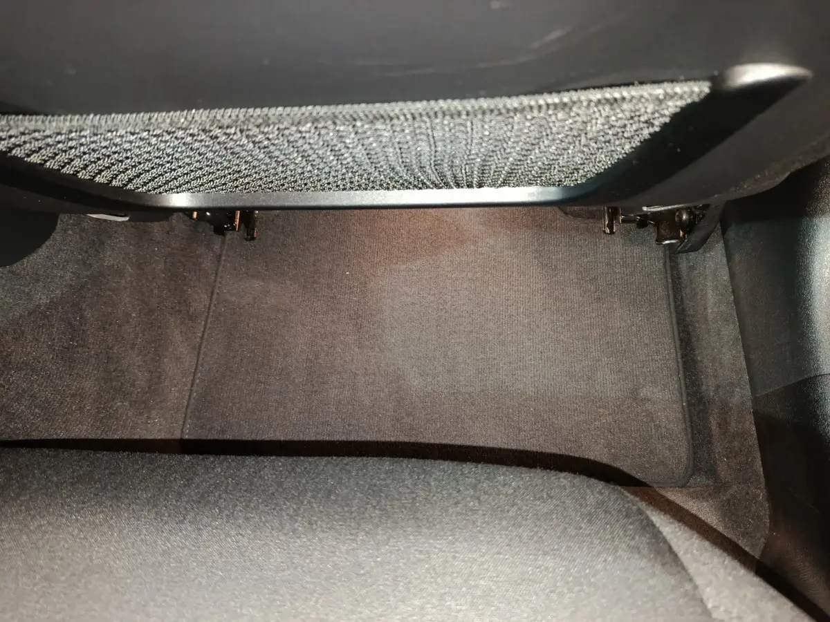 Espace au sol côté passager avant de la BMW Série 3 316d 2022 avec tapis gris foncé et filet de rangement sous tableau de bord.