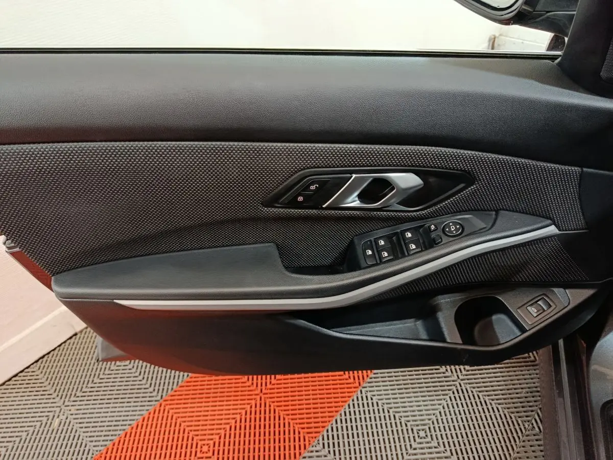 Détail de la porte côté gauche de la BMW Série 3 316d 2022 avec commandes de vitres et poignée argentée.