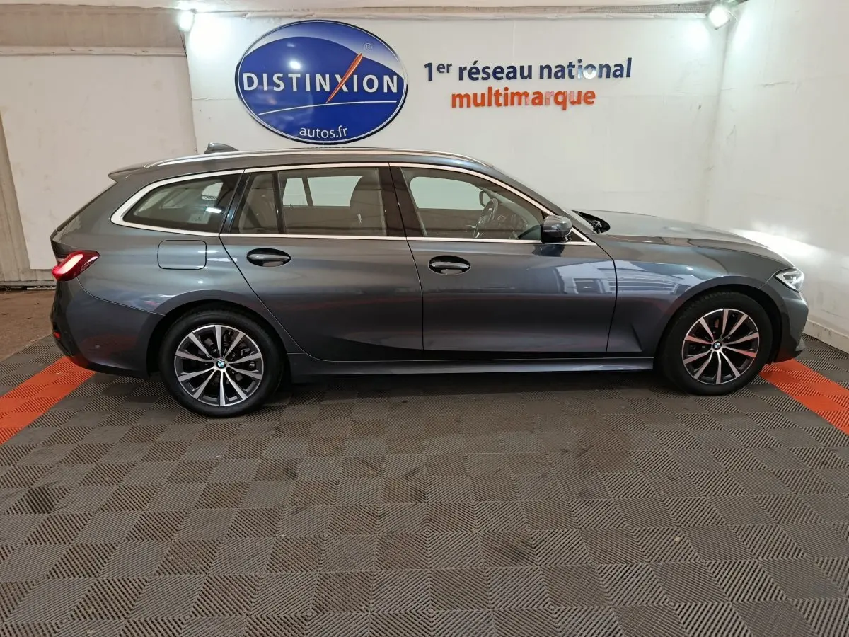 BMW Série 3 316d gris clair vue de profil côté gauche dans un showroom avec logo Distinxion en arrière-plan.