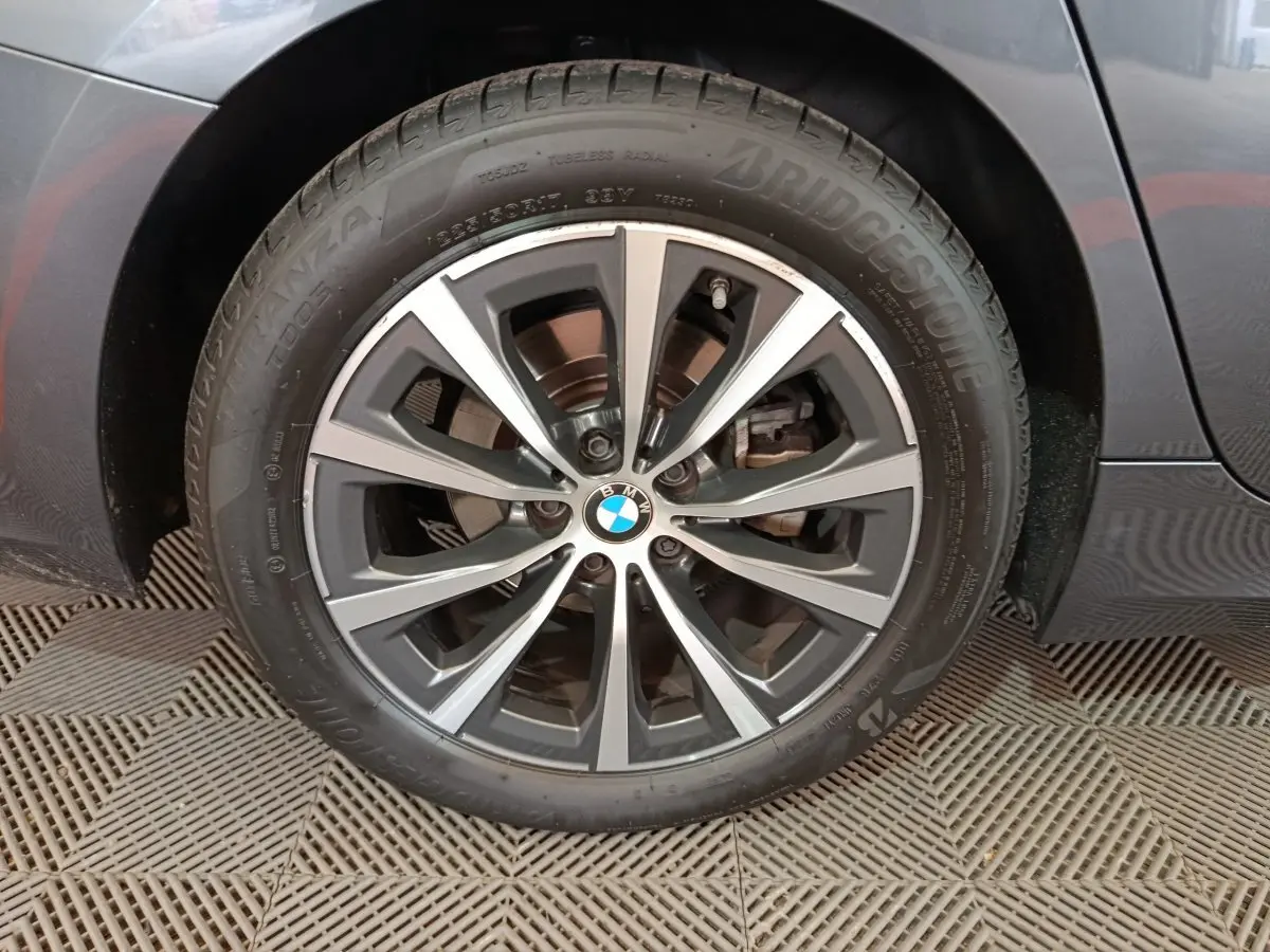 Gros plan sur la roue avant gauche gris clair d'une BMW Série 3 316d avec jante alliage et logo BMW central.