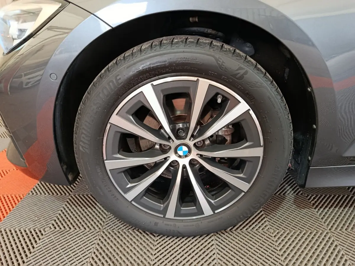 Gros plan sur la roue avant gauche gris clair d'une BMW Série 3 316d avec jante alliage et logo BMW central.