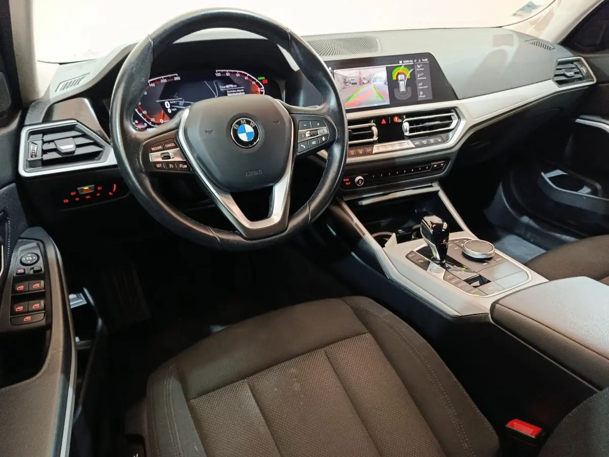 Intérieur BMW Série 3 316d 2022 vu côté conducteur, volant cuir, tableau de bord digital et écran tactile central.